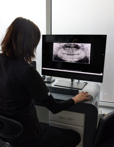 Lekarz stomatolog analizujący zdjęcie panoramiczne zębów pacjenta w gabinecie.